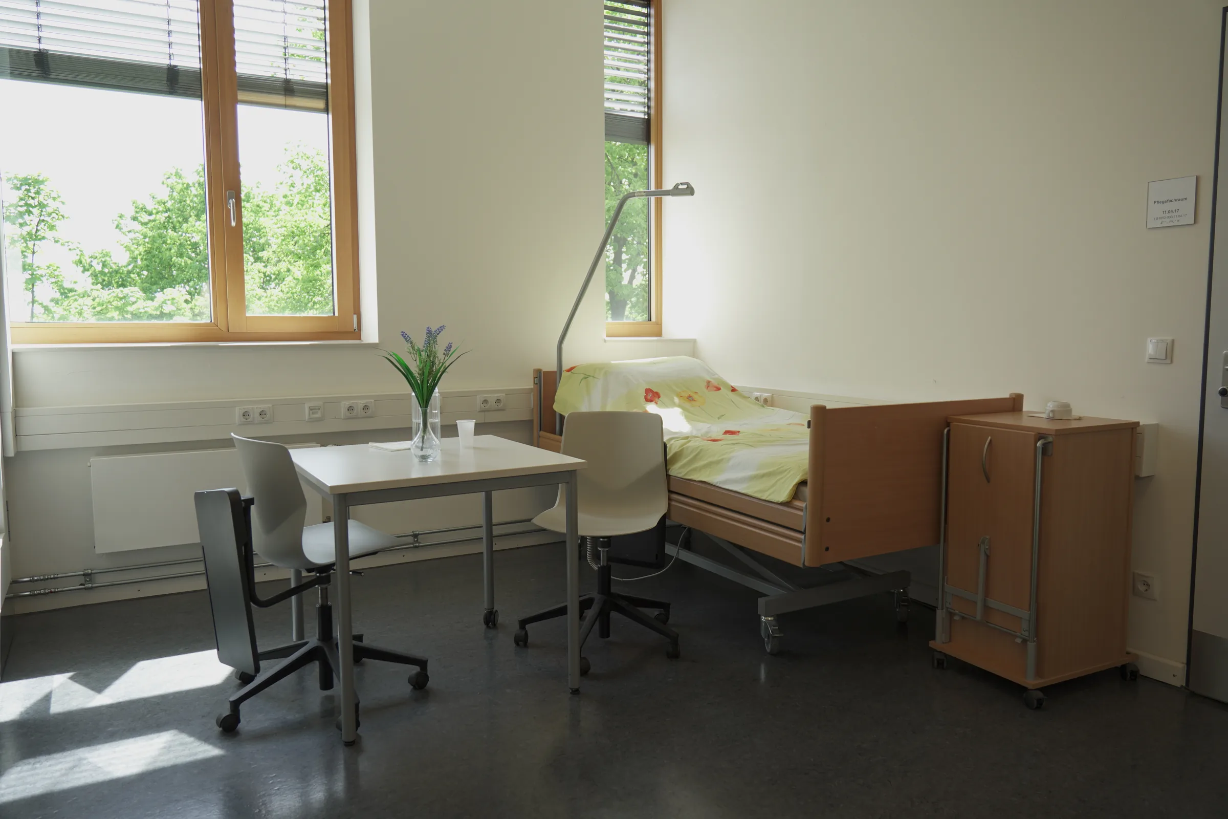 Übungsraum mit Pflegebett, Tisch und Stühlen in einem Skills Lab